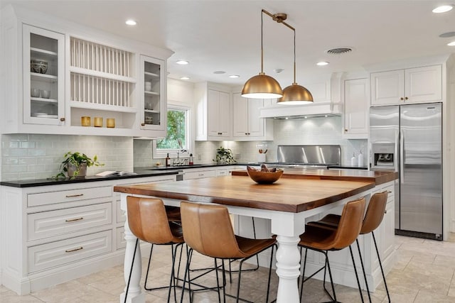 4607 Balcones Dr, Austin, TX 78731 - kitchen featuring stainless steel fridge, butcher block countertops, range, a breakfast bar area, and white cabinetry