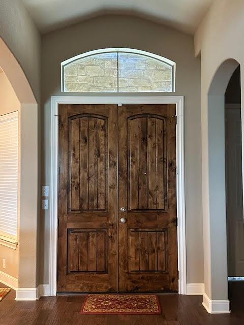21912 Rock Wren Rd, Spicewood, TX 78669 - entrance foyer featuring dark wood-style flooring, vaulted ceiling, arched walkways, and baseboards