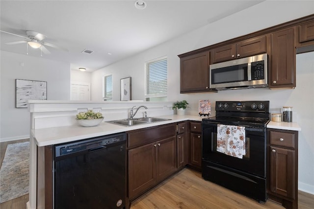 129 Syrah Ct, Leander, TX 78641 - kitchen featuring black appliances, a sink, light wood-style flooring, and a peninsula