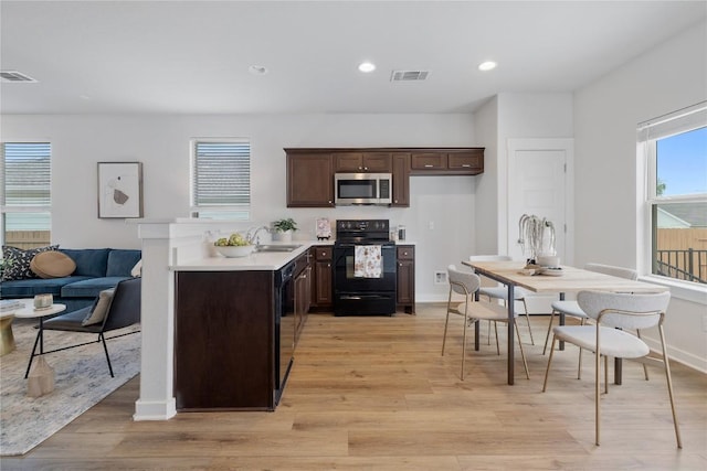 129 Syrah Ct, Leander, TX 78641 - kitchen featuring black appliances, dark brown cabinetry, a sink, light countertops, and light wood finished floors