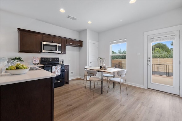129 Syrah Ct, Leander, TX 78641 - kitchen featuring stainless steel microwave, black range with electric cooktop, dark brown cabinetry, light wood-style floors, and light countertops