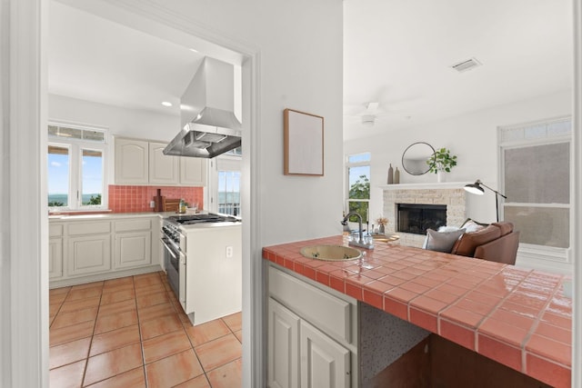 5913 N W Pl, Austin, TX 78731 - kitchen featuring island range hood, high end stove, tasteful backsplash, light tile patterned floors, and plenty of natural light