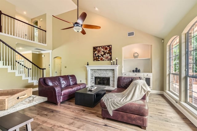 10672 Bramblecrest Dr, Austin, TX 78726 - living area featuring arched walkways, high vaulted ceiling, a glass covered fireplace, a ceiling fan, and wood finished floors