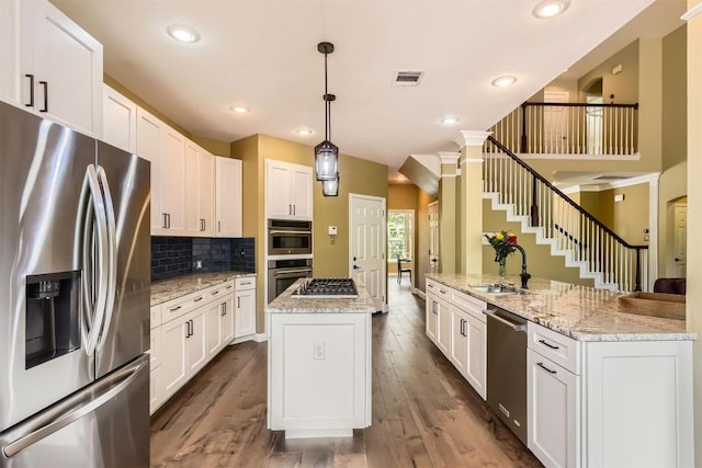 10672 Bramblecrest Dr, Austin, TX 78726 - kitchen featuring appliances with stainless steel finishes, a center island with sink, a sink, decorative backsplash, and white cabinets