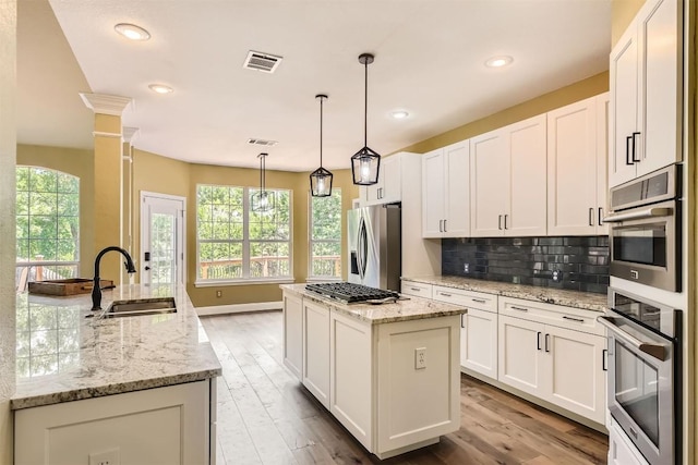 10672 Bramblecrest Dr, Austin, TX 78726 - kitchen featuring a sink, a center island, stainless steel appliances, backsplash, and white cabinetry
