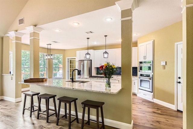 10672 Bramblecrest Dr, Austin, TX 78726 - kitchen with a sink, stainless steel appliances, white cabinets, light wood-type flooring, and a kitchen breakfast bar