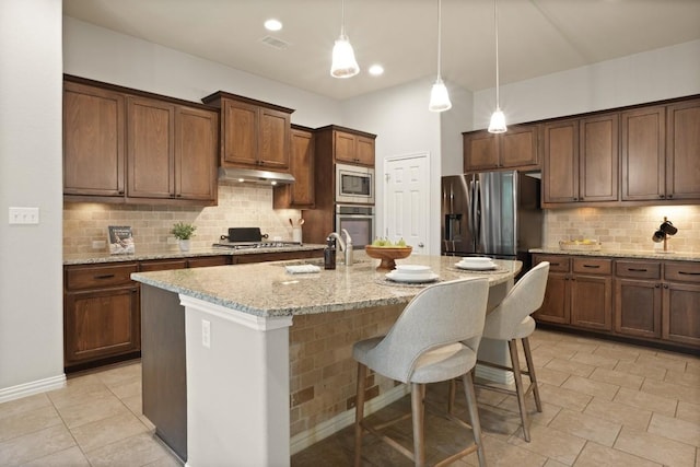 495 Catalina Ln, Austin, TX 78737 - kitchen with appliances with stainless steel finishes, a sink, decorative backsplash, a kitchen bar, and a kitchen island with sink