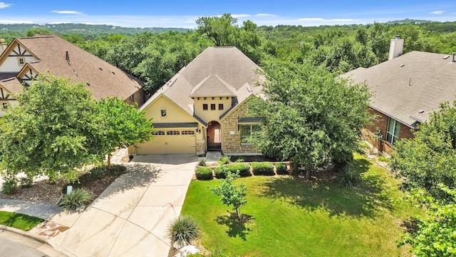 495 Catalina Ln, Austin, TX 78737 - view of front of home featuring concrete driveway, stucco siding, an attached garage, stone siding, and a wooded view