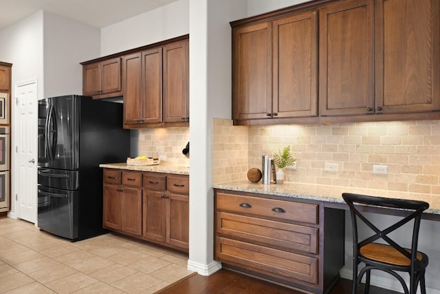 495 Catalina Ln, Austin, TX 78737 - kitchen featuring black refrigerator with ice dispenser, light stone countertops, double oven, decorative backsplash, and a kitchen bar
