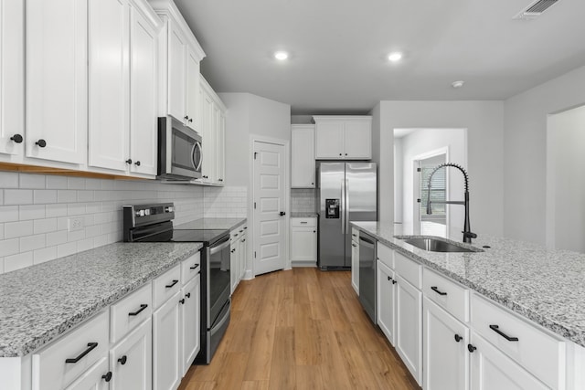 9513 Balmy Ln, Manor, TX 78653 - kitchen with stainless steel appliances, a sink, white cabinets, light wood-type flooring, and recessed lighting