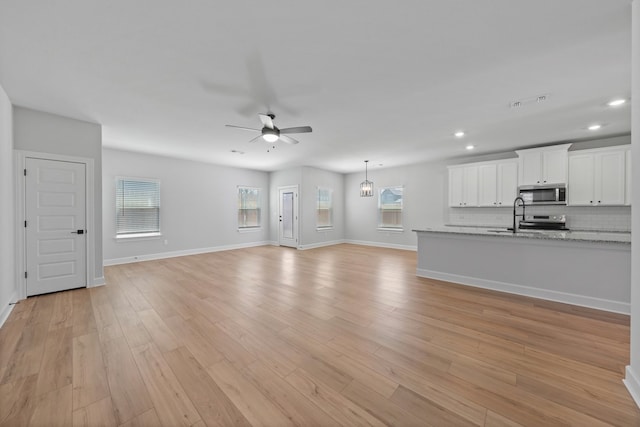 9513 Balmy Ln, Manor, TX 78653 - unfurnished living room with a ceiling fan, recessed lighting, light wood-style flooring, a sink, and baseboards
