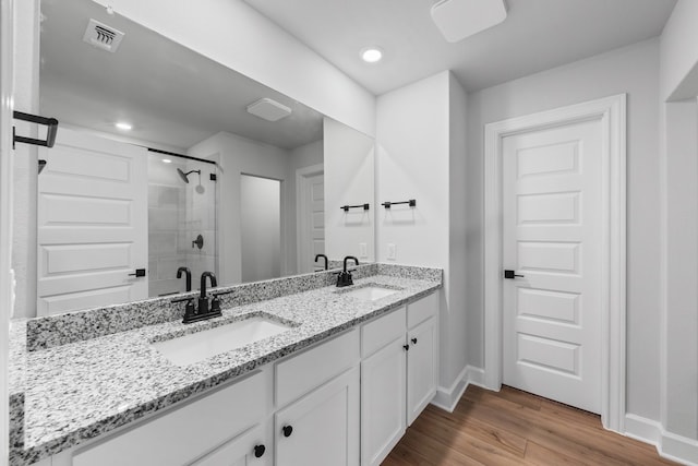 9513 Balmy Ln, Manor, TX 78653 - bathroom with baseboards, double vanity, a shower stall, wood finished floors, and recessed lighting