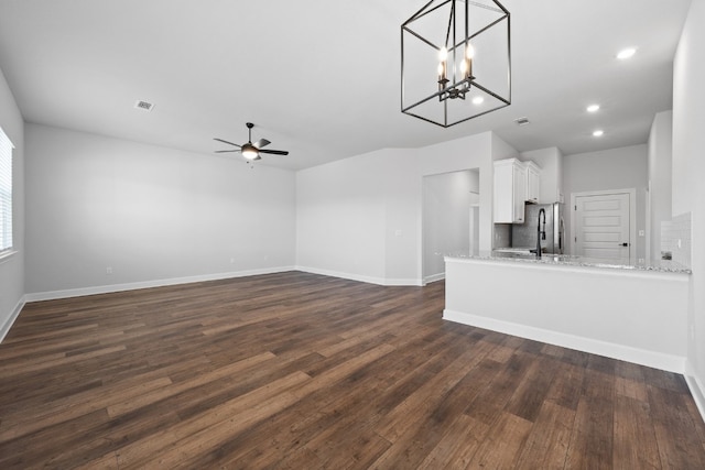 9709 Gladsome Path, Manor, TX 78653 - unfurnished living room featuring a ceiling fan, dark wood-style flooring, baseboards, a chandelier, and recessed lighting