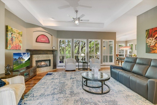 12505 Stapp Ct, Austin, TX 78732 - living area with a tray ceiling, wood finished floors, a ceiling fan, and a tiled fireplace