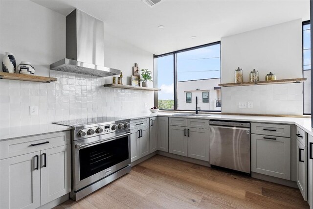 1800 E 4th St Unit 396, Austin, TX 78702 - kitchen with open shelves, stainless steel appliances, wall chimney exhaust hood, and gray cabinets