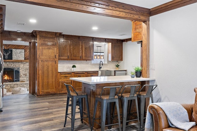 119 Vicinity Trl, Spicewood, TX 78669 - kitchen featuring tasteful backsplash, a kitchen breakfast bar, a sink, light countertops, and dark wood-style flooring