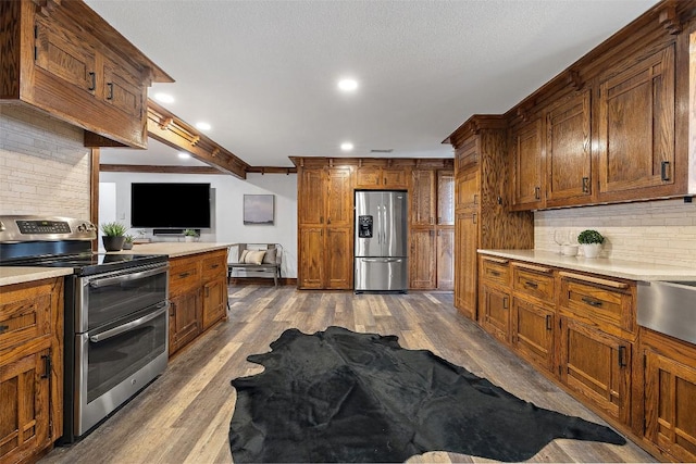 119 Vicinity Trl, Spicewood, TX 78669 - kitchen featuring stainless steel appliances, dark wood finished floors, tasteful backsplash, light countertops, and brown cabinetry