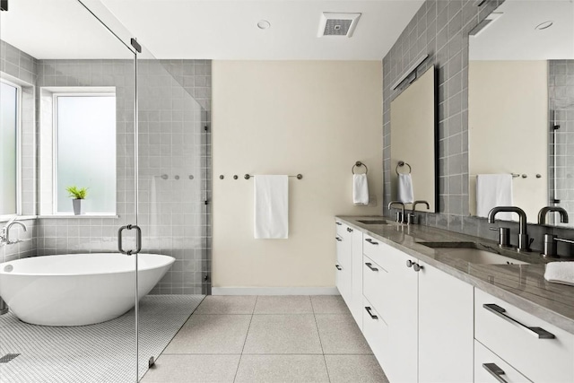 4005 Knollwood Dr, Austin, TX 78731 - bathroom featuring double vanity, tile walls, a freestanding tub, tile patterned flooring, and a stall shower