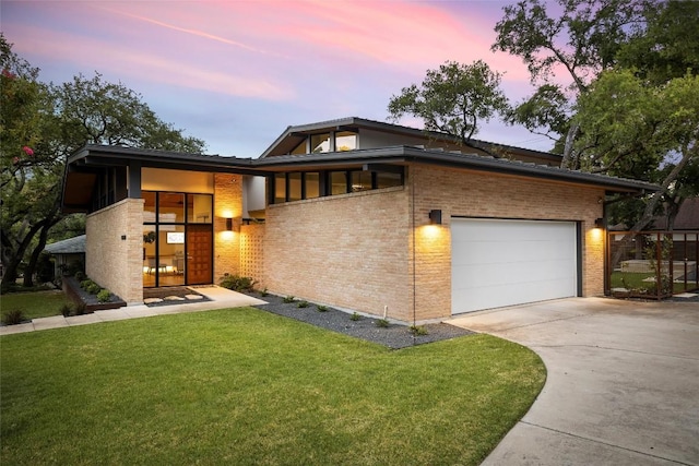 4005 Knollwood Dr, Austin, TX 78731 - contemporary house featuring a garage, concrete driveway, a front lawn, and brick siding