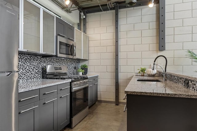 4801 S Congress Ave Unit A1, Austin, TX 78745 - kitchen with appliances with stainless steel finishes, gray cabinetry, concrete flooring, light stone countertops, and backsplash