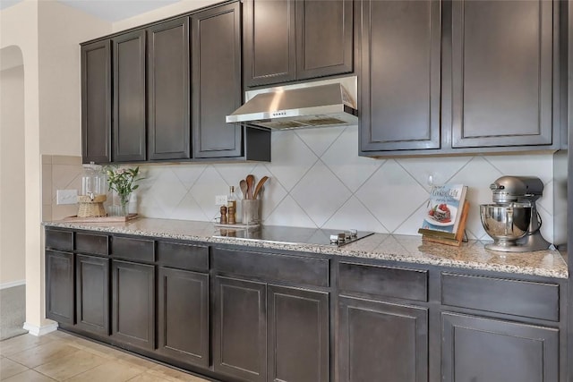 351 Jarbridge Dr, Kyle, TX 78640 - kitchen featuring wall chimney range hood, black electric stovetop, backsplash, light stone counters, and dark brown cabinets