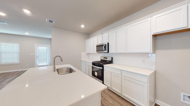 4019 Illian Cv, Killeen, TX 76542 - kitchen with stainless steel appliances, a sink, light wood-style floors, white cabinetry, and tasteful backsplash