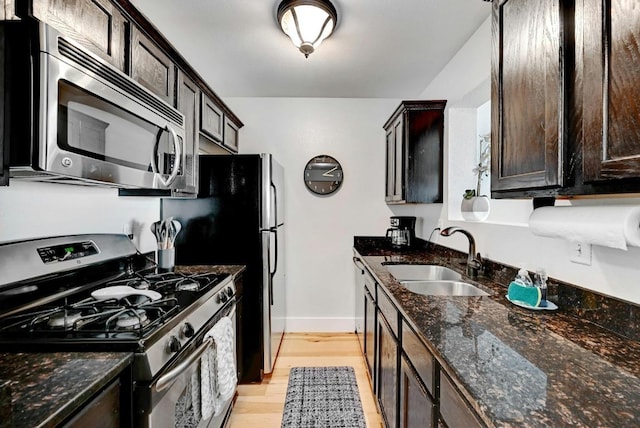 1307 Norwalk Ln Unit 104, Austin, TX 78703 - kitchen with stainless steel appliances, a sink, dark brown cabinets, light wood-type flooring, and dark stone counters