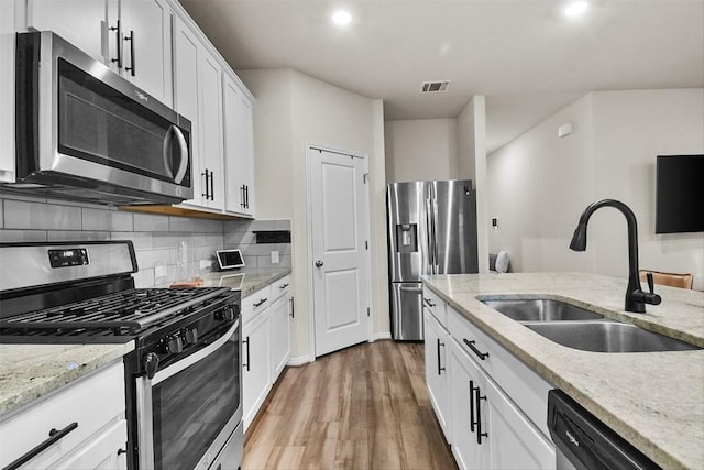 801 Russet Rock Dr Unit 6, Manchaca, TX 78748 - kitchen with appliances with stainless steel finishes, a sink, light wood finished floors, tasteful backsplash, and white cabinetry