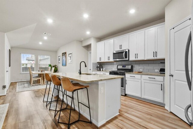 801 Russet Rock Dr Unit 6, Manchaca, TX 78748 - kitchen with appliances with stainless steel finishes, a sink, tasteful backsplash, a breakfast bar, and a kitchen island with sink