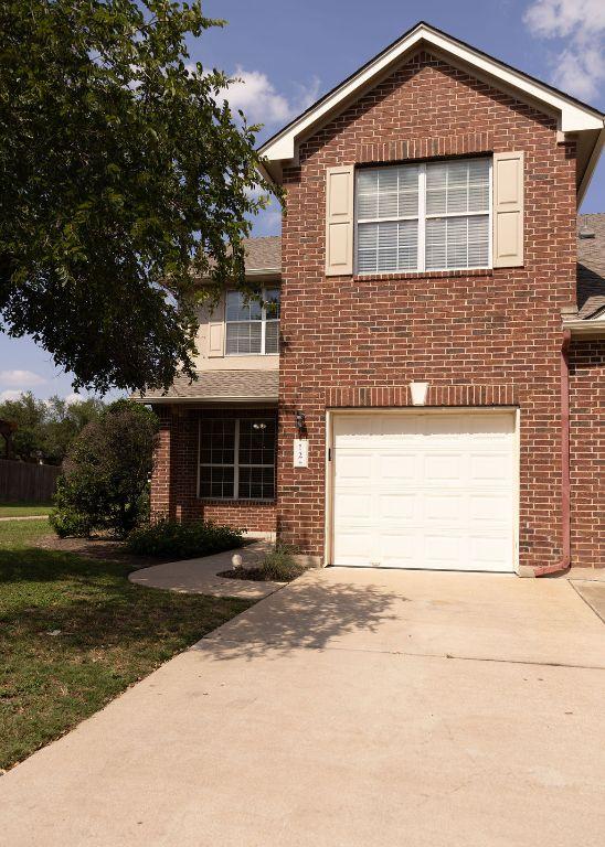 12 Verde Ranch Loop, Leander, TX 78641 - view of front of home with brick siding, driveway, an attached garage, a front yard, and a shingled roof
