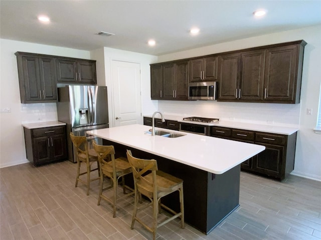 19024 Fernando Trl, Austin, TX 78738 - kitchen featuring stainless steel appliances, a sink, a kitchen breakfast bar, light wood finished floors, and recessed lighting