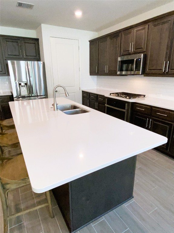 19024 Fernando Trl, Austin, TX 78738 - kitchen with appliances with stainless steel finishes, a sink, a center island with sink, light countertops, and a breakfast bar