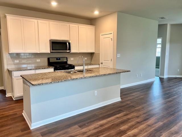 232 Serpens St, Georgetown, TX 78628 - kitchen with stainless steel microwave, black range oven, decorative backsplash, a center island with sink, and recessed lighting