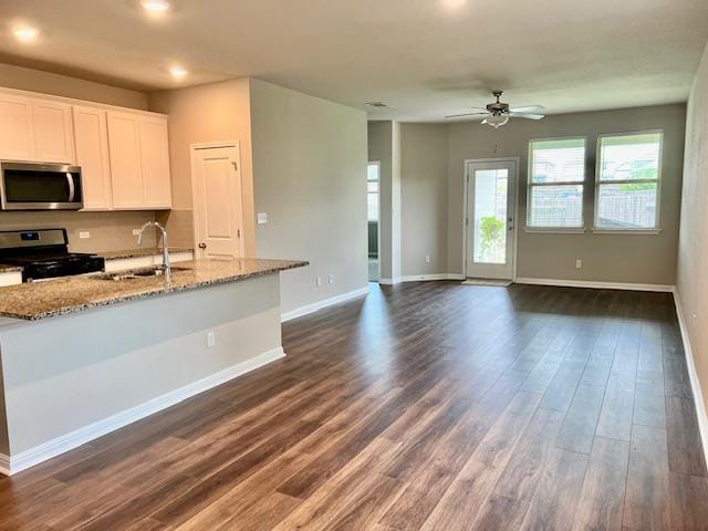 232 Serpens St, Georgetown, TX 78628 - kitchen featuring stainless steel microwave, gas range oven, dark wood finished floors, light stone counters, and white cabinets