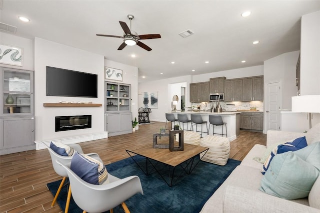 620 Saturnia Dr, Georgetown, TX 78628 - living room with ceiling fan, wood finished floors, a glass covered fireplace, and recessed lighting