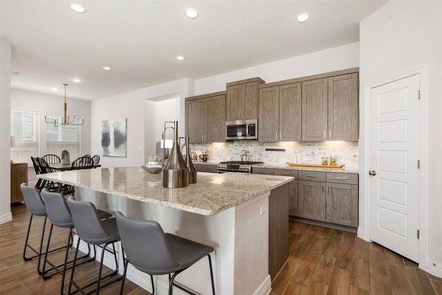 620 Saturnia Dr, Georgetown, TX 78628 - kitchen with stainless steel appliances, tasteful backsplash, light stone countertops, a breakfast bar, and a center island with sink