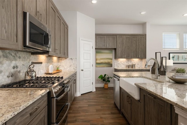 620 Saturnia Dr, Georgetown, TX 78628 - kitchen with stainless steel appliances, dark wood-style flooring, backsplash, light stone counters, and recessed lighting