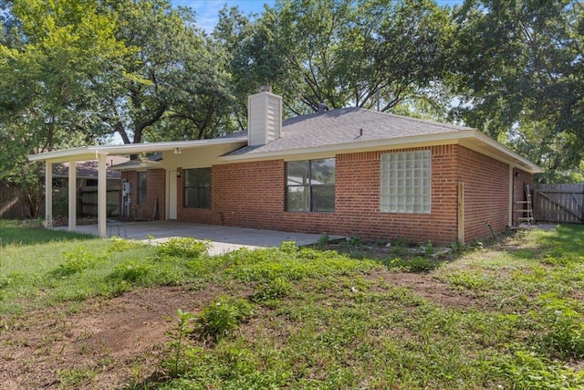 910 Garwood St, Smithville, TX 78957 - back of house featuring brick siding, a chimney, and a patio