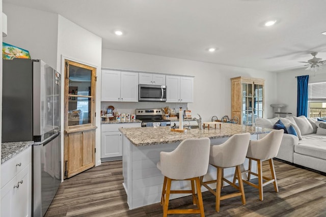 121 Rubrum Rd, Kyle, TX 78640 - kitchen featuring stainless steel appliances, open floor plan, a breakfast bar, a ceiling fan, and white cabinets