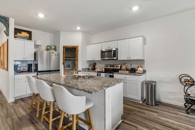 121 Rubrum Rd, Kyle, TX 78640 - kitchen featuring appliances with stainless steel finishes, a kitchen bar, dark wood-type flooring, an island with sink, and recessed lighting