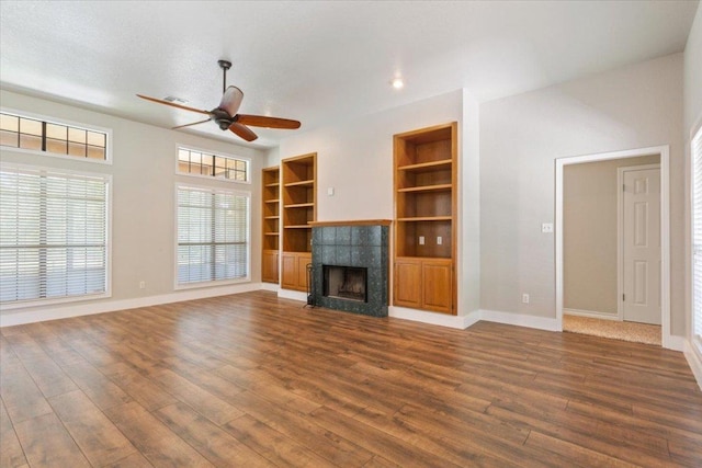3609 Walter Ln, Belton, TX 76513 - unfurnished living room featuring dark wood-style floors, ceiling fan, baseboards, a tile fireplace, and built in shelves