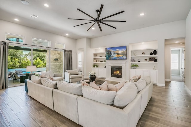 206 Bridge Water Loop, Dripping Springs, TX 78620 - living room featuring wood finished floors, recessed lighting, a glass covered fireplace, baseboards, and a ceiling fan