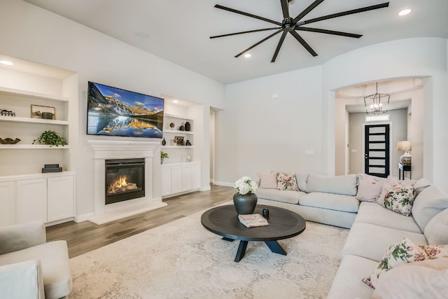 206 Bridge Water Loop, Dripping Springs, TX 78620 - living room with wood finished floors, a glass covered fireplace, built in features, a chandelier, and recessed lighting