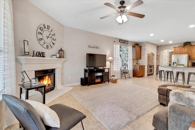 167 Limestone Trl Unit 76, Austin, TX 78737 - living area featuring arched walkways, a glass covered fireplace, ceiling fan, recessed lighting, and light tile patterned flooring