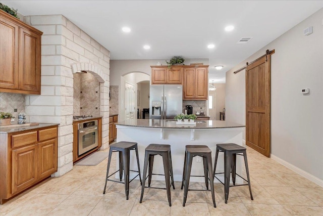 167 Limestone Trl Unit 76, Austin, TX 78737 - kitchen featuring appliances with stainless steel finishes, decorative backsplash, a breakfast bar, a barn door, and recessed lighting