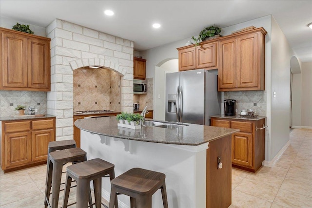 167 Limestone Trl Unit 76, Austin, TX 78737 - kitchen with stainless steel appliances, a sink, arched walkways, dark stone countertops, and tasteful backsplash