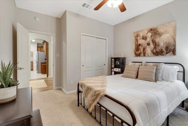 167 Limestone Trl Unit 76, Austin, TX 78737 - bedroom with freestanding refrigerator, a closet, light colored carpet, arched walkways, and ceiling fan