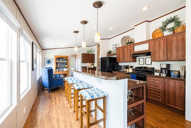 231 Wolf Run, Burnet, TX 78611 - kitchen featuring black appliances, healthy amount of natural light, brown cabinets, wood finished floors, and crown molding