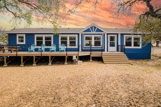 231 Wolf Run, Burnet, TX 78611 - back of property at dusk featuring a wooden deck and roof with shingles