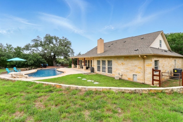 529 Honeycomb Cir, Driftwood, TX 78619 - back of property featuring stone siding, central AC unit, a patio area, a chimney, and an outdoor pool